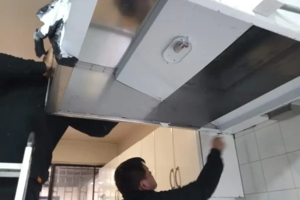 Campana de acero inoxidable de gran formato instalada en el cielo de una cocina industrial en operación