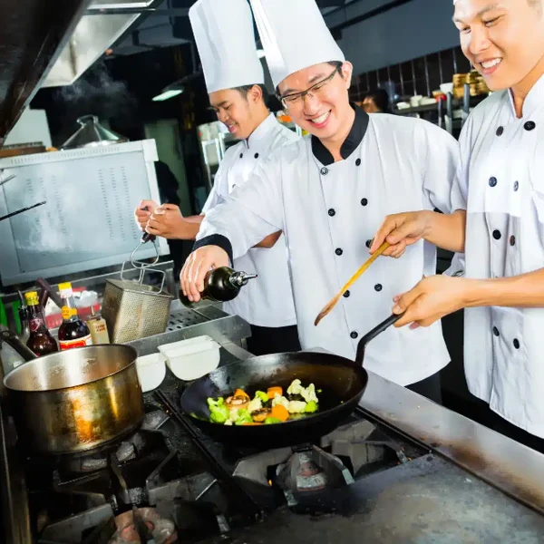 Cocineros preparando alimentos en una cocina industrial