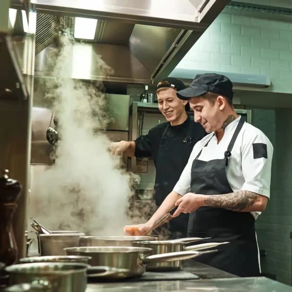 Cocineros trabajando entre el vapor de una cocina abierta